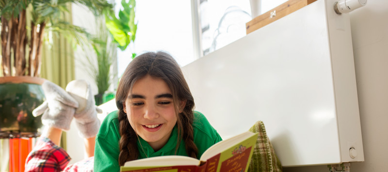 foto van een meisje dat een boek leest in een warm huis